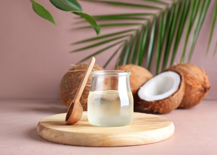 Pure virgin coconut oil in a glass jar placed next to fresh coconut meat, highlighting its natural and organic source